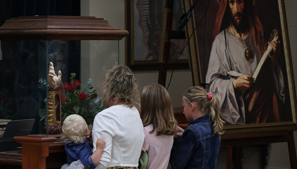 A family of 4 visiting the Arm of Saint Jude in La Crosse, Wisconsin, the traveling relic.