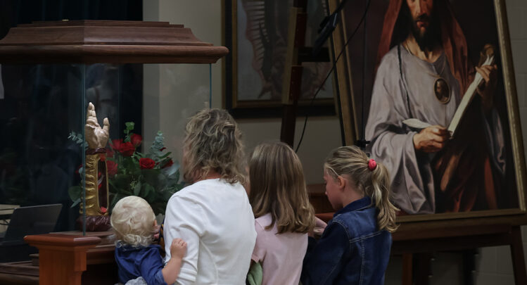 A family of 4 visiting the Arm of Saint Jude in La Crosse, Wisconsin, the traveling relic.