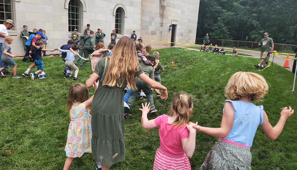 A scattered group of families with their children running and playing games in the grass.