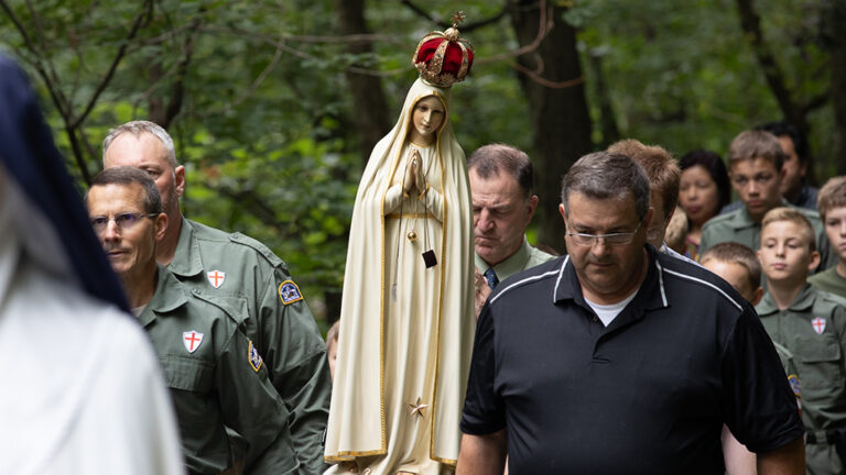 The weeping statue of Our Lady of Fatima being carried by a small group of men during the procession of Saint George.