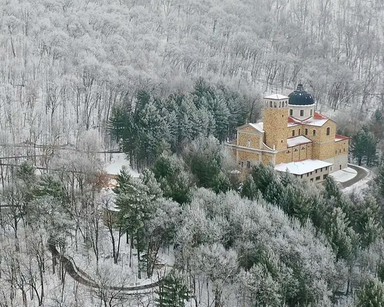 Snow covering the church building and surrounding trees of Our Lady of Guadalupe Shrine in La Crosse, Wisconsin.