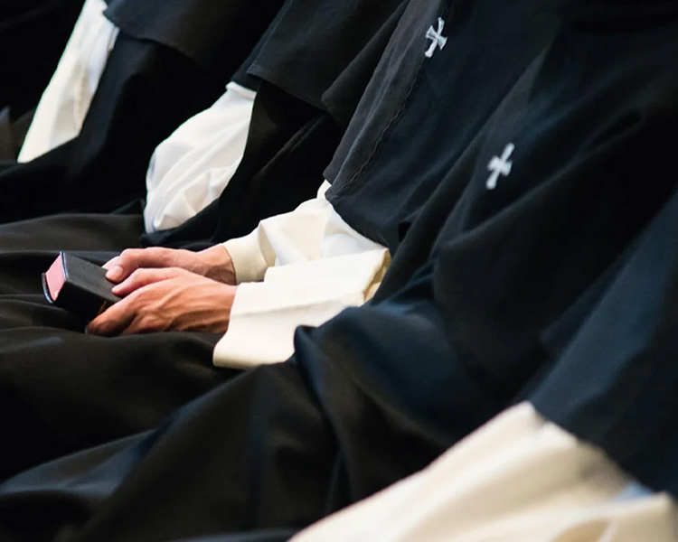 A person wearing the Dominican influence cape and holding a bible in the congregation of the church at Our Lady of Guadalupe Shrine in La Crosse, Wisconsin.