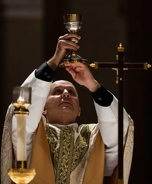 Father Check holding a communal wine glass during mass at Our Lady of Guadalupe Shrine in La Crosse, Wisconsin.