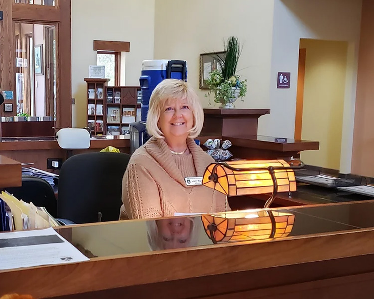 Front desk volunteer smiling in the reception area of Our Lady of Guadalupe Shrine in La Crosse, Wisconsin.