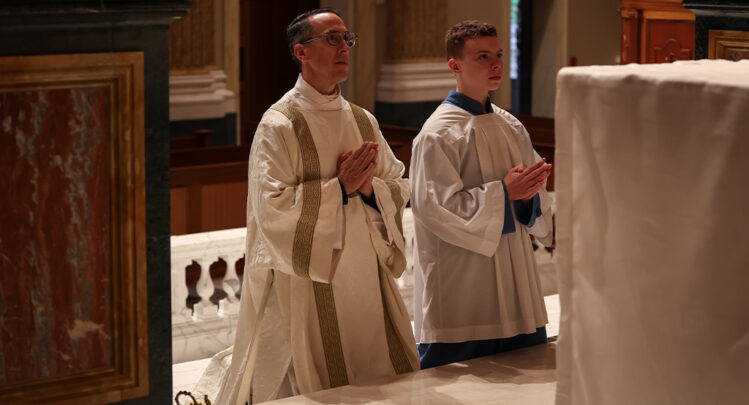 Deacon Kabat and his Altar Server son kneeled before the altar focused in prayer.