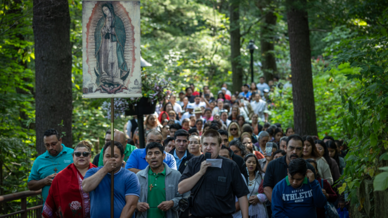 A man carrying an image of Lady Guadalupe leads hundreds of people through the pathway of Our Lady of Guadalupe Shrine for Our Lady's Nativity in La Crosse, Wisconsin.