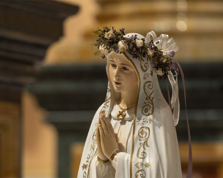 Statue of Mary wearing a floral crown wreath and praying at Our Lady of Guadalupe Shrine in La Crosse, Wisconsin.