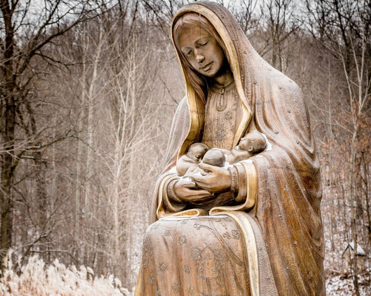 Statue of Our Lady of Guadalupe holding three babies in winter outside of the Memorial to the Unborn at Our Lady of Guadalupe Shrine in La Crosse, Wisconsin.