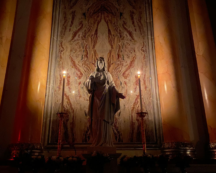 Statue of Mother Mary in between two lit candles at Our Lady of Guadalupe Shrine in La Crosse, Wisconsin.