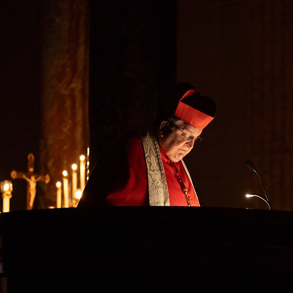 A candle-lit shot of Cardinal Burke focusing on his readings.