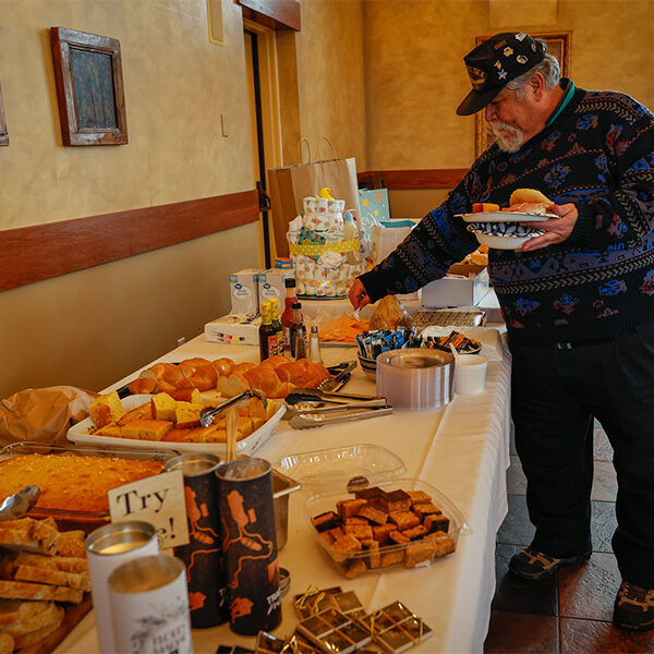 A man grabbing food at the food table during the chili cookoff.