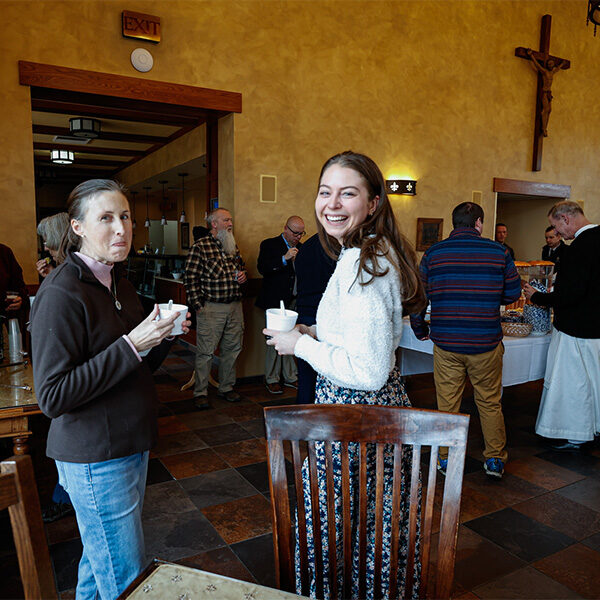 Emily and Jen laughing together while enjoying their cup of chili from the chili cookoff in the Shrine banquet hall.