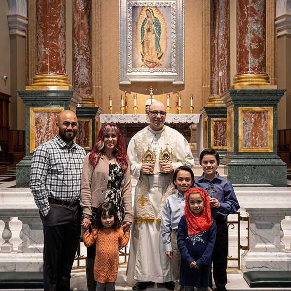 A pilgrimage family of 6 posting for a picture with the Shrine's priest.