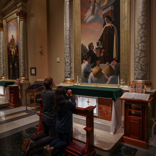 A newlywed couple kneeled in front of side alter to pray in the Shrine Church located in La Crosse, Wisconsin.