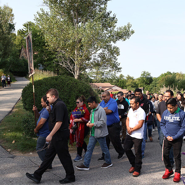 On Hispanic Day of Pilgrimage, a group of Hispanics are participating in an uphill procession with Our Lady of Guadalupe in La Crosse, Wisconsin.