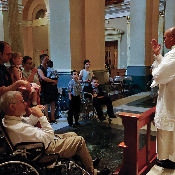 A Norbertine priest blesses two people in wheelchairs from the Nunes family.