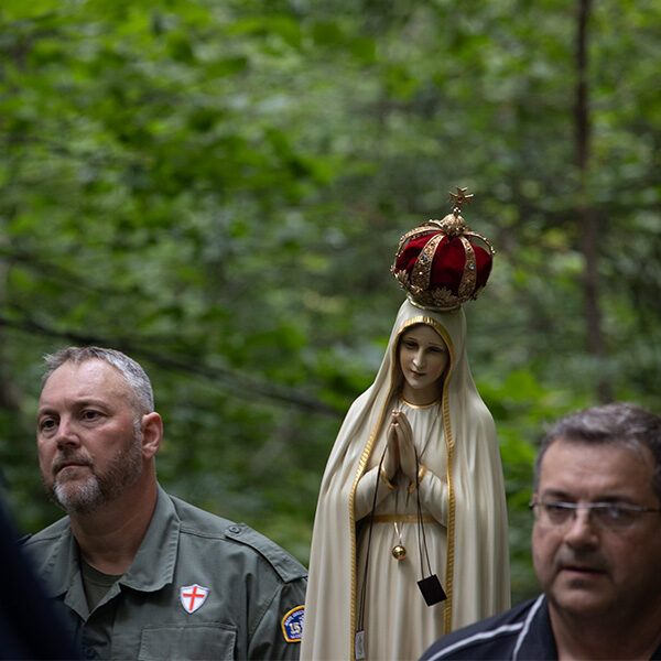 Closeup of two men carrying Our Lady of Fatima statue uphill during procession.