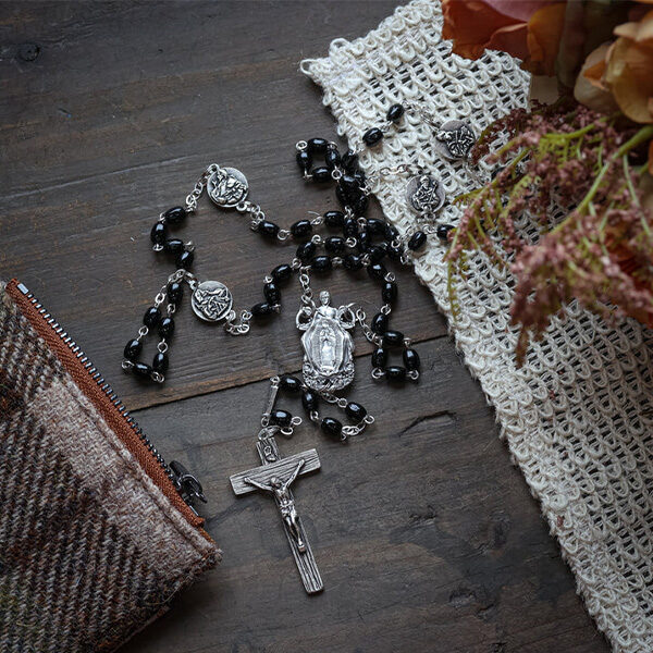 A St. Juan Diego rosary laying on a wood table display.