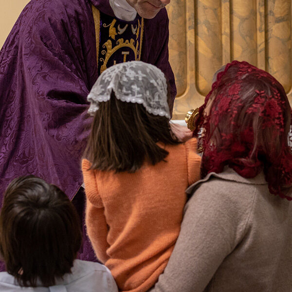 A mother and daughter wearing a lacey floral veil during a relic veneration.