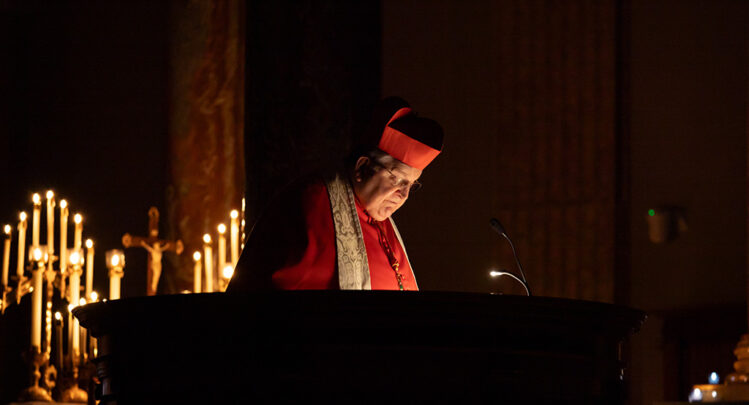 A candle-lit shot of Cardinal Burke focusing on his readings.