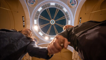 A worm's eye view of a newlywed couple holding hands under the blue church dome at the Shrine.