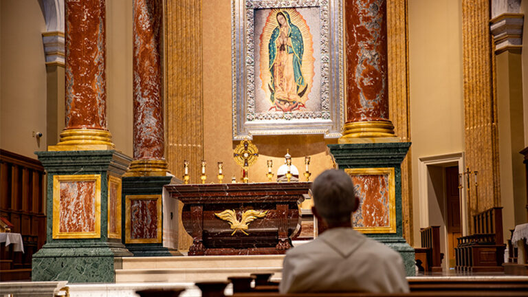 what is a pilgrimage - norbertine praying in church with eucharistic adoration with tilma of mary in background