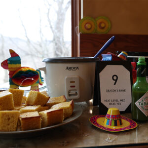 Guadalupe Shrine Chili Cookoff contestant Green Verde Chili with Cornbread and colorful festive decorations includes hat and pinata