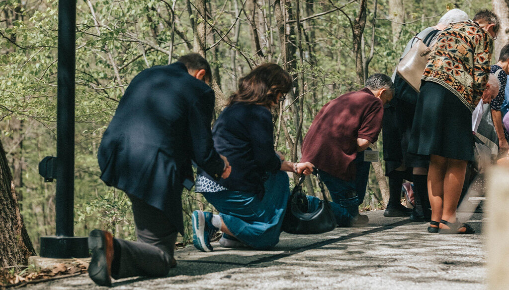 Pilgrims Genuflecting or kneeling at the outdoor stations of the cross