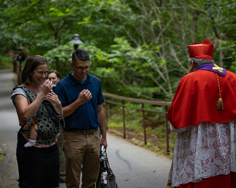 Cardinal Burke Bless a couple with a child on pilgrimage