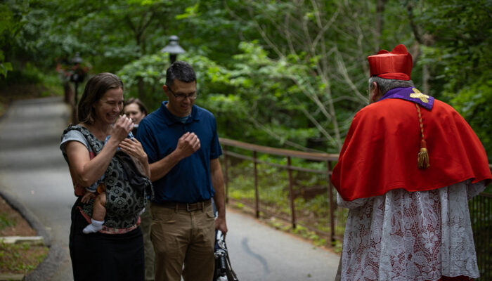 Couple being blessed with their child by Cardinal Burke