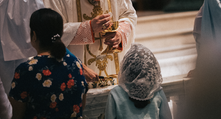 Young Catholic receiving communion at the communion rail