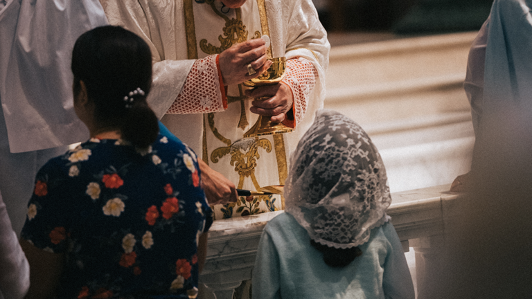 Young Catholic receiving communion at the communion rail