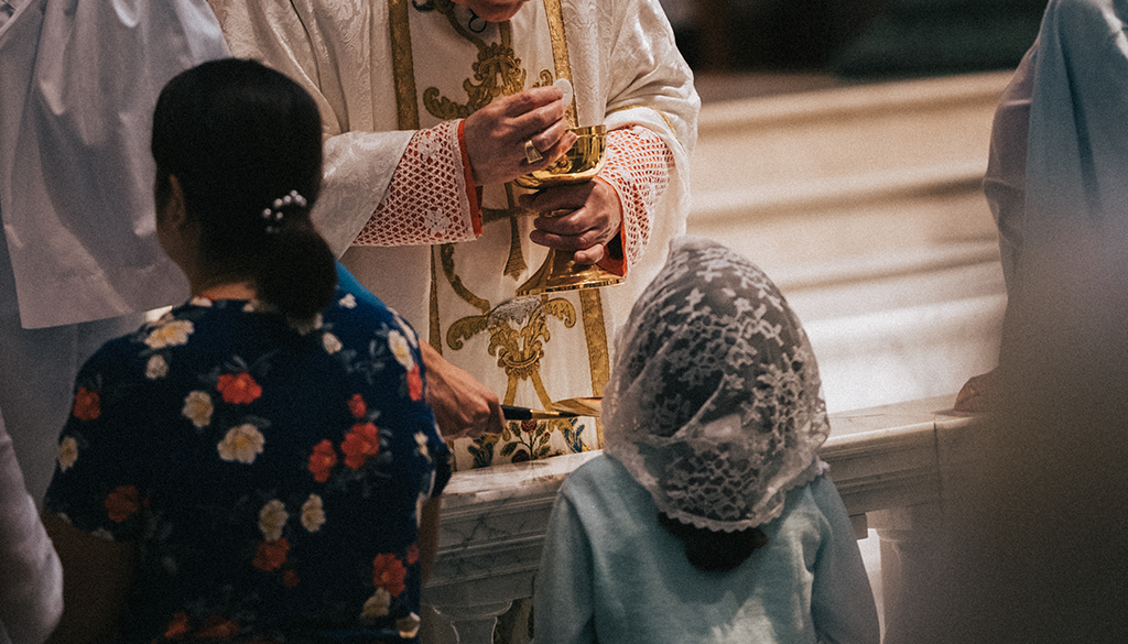 Young Catholic receiving communion at the communion rail