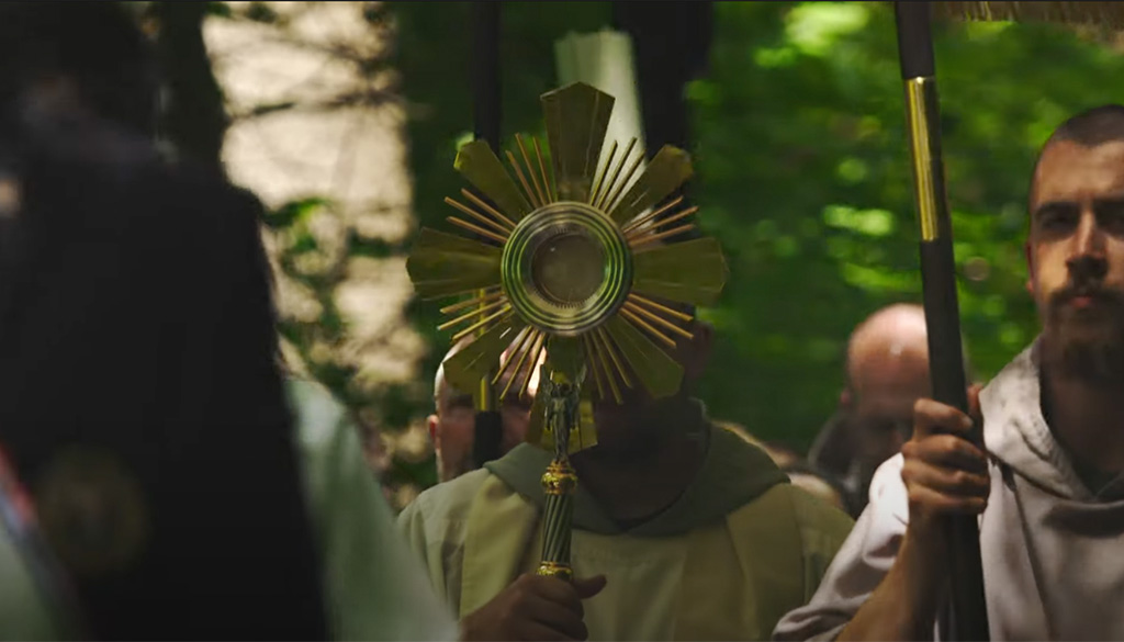 A religious procession at the Shrine of Our Lady of Guadalupe in La Crosse, Wisconsin, featuring a cleric holding a golden monstrance during a sacred Eucharistic ritual, as part of a video titled 'Holy Eucharist: Jesus Fulfills His Promise' by Father Paul Check on June 18, 2024.