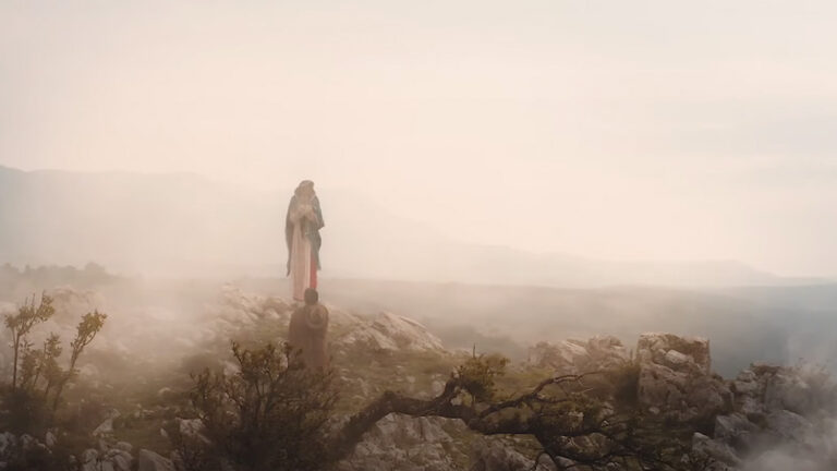 A serene misty landscape with a figure kneeling before the Shrine of Our Lady Guadalupe, set atop a rocky terrain in La Crosse, Wisconsin.