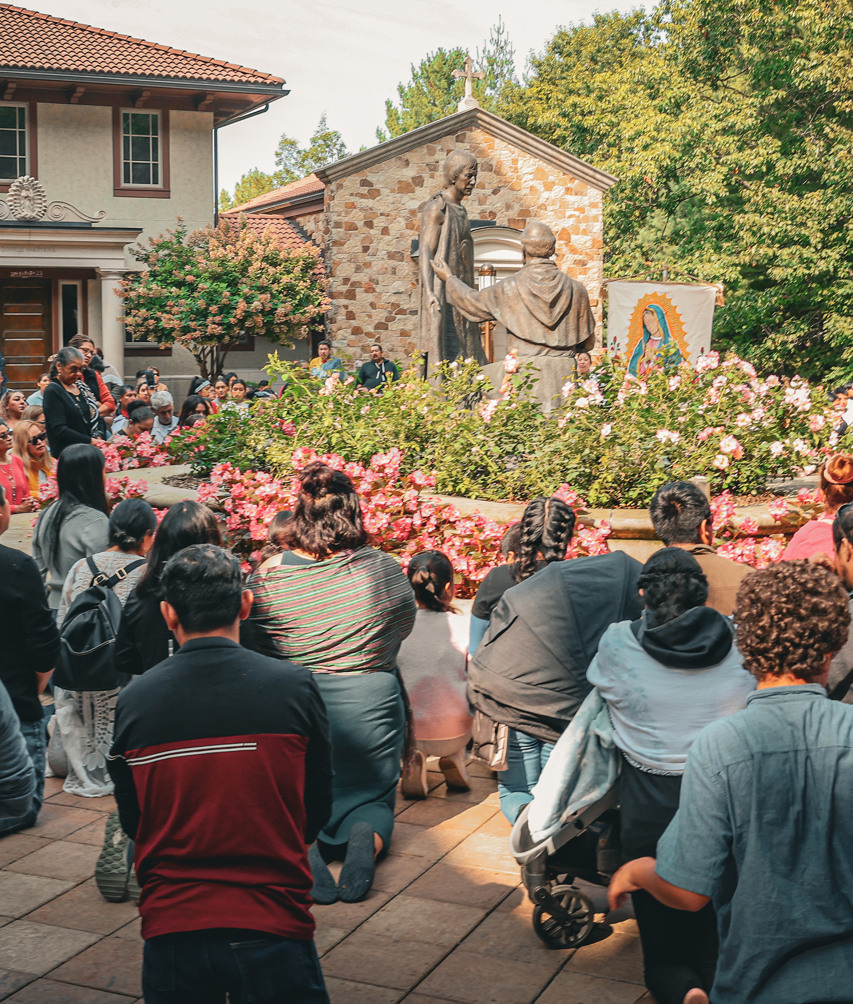 Pilgrims pray around the statue of Saint Juan Diego and Bishop Juan de Zumárraga in the plaza of the Shrine Church.